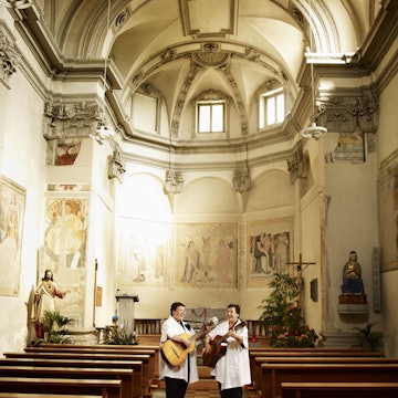 Two women singing and playing guitar in Bedigliora’s church.