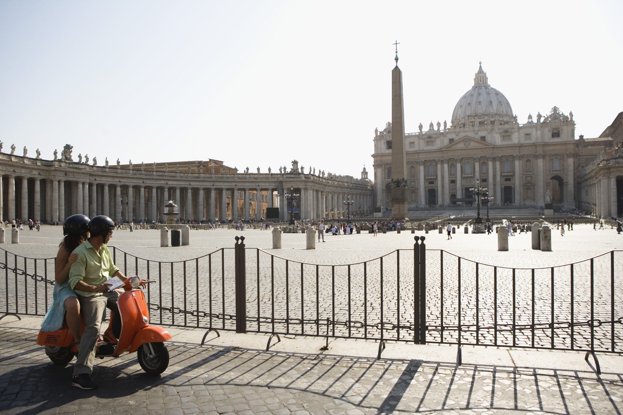 A couple on a scooter looking over at St Peter's Basilica and the piazza outside it