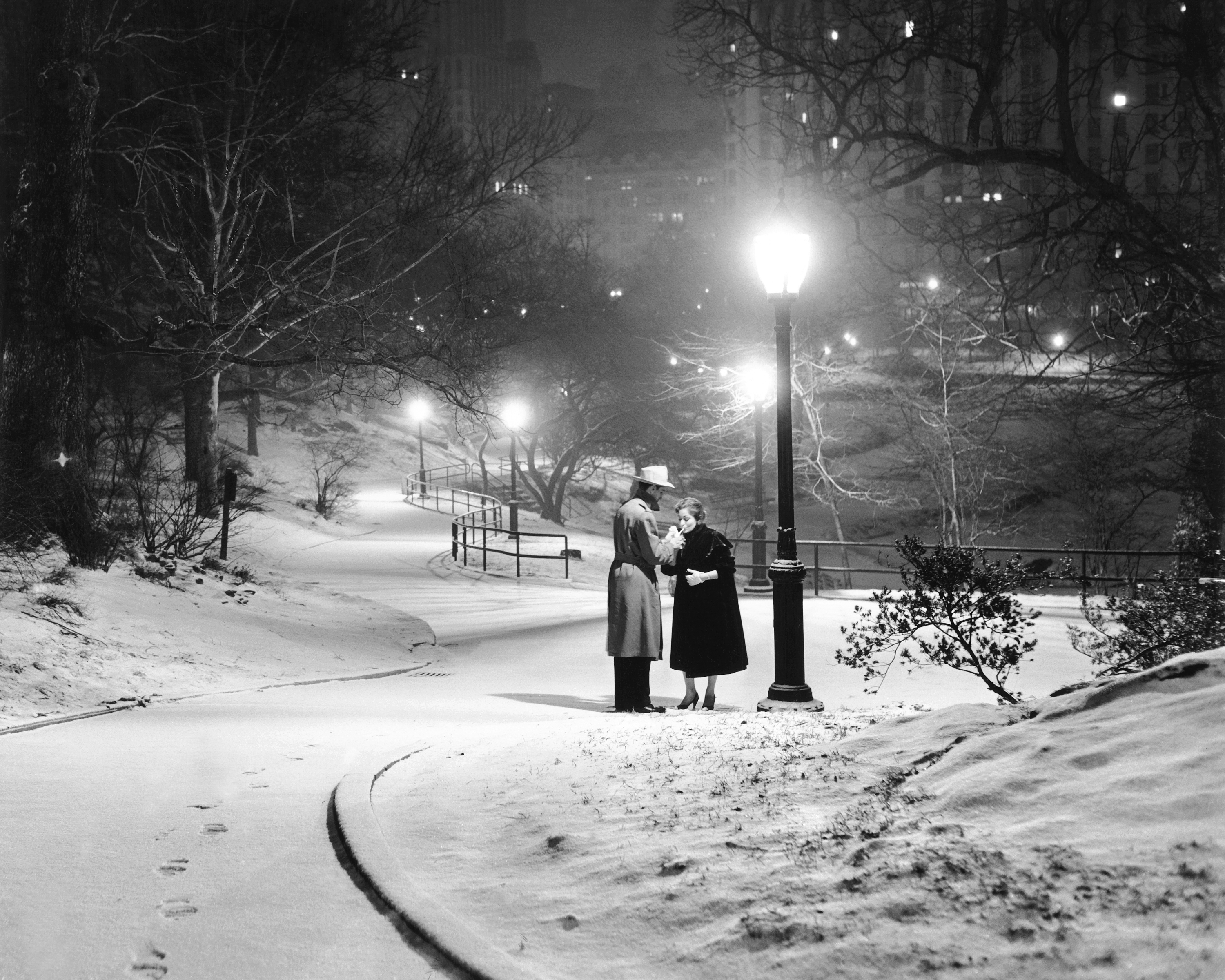 A couple pauses for a cigarette in snowy Central Park.
