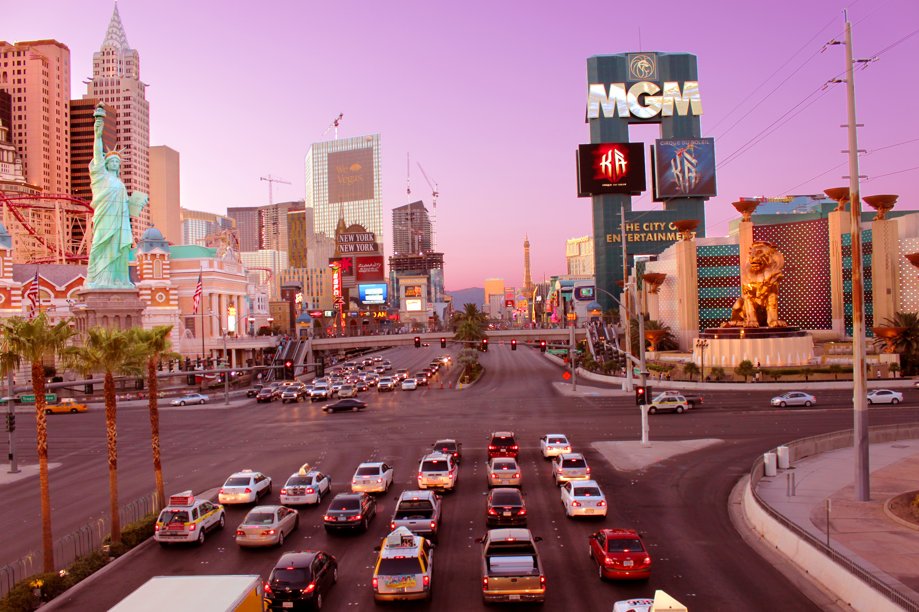 Queues of cars wait at the traffic lights on the Las Vegas strip near the intersection of the MGM Grand hotel and casino with a pink sunset in the background