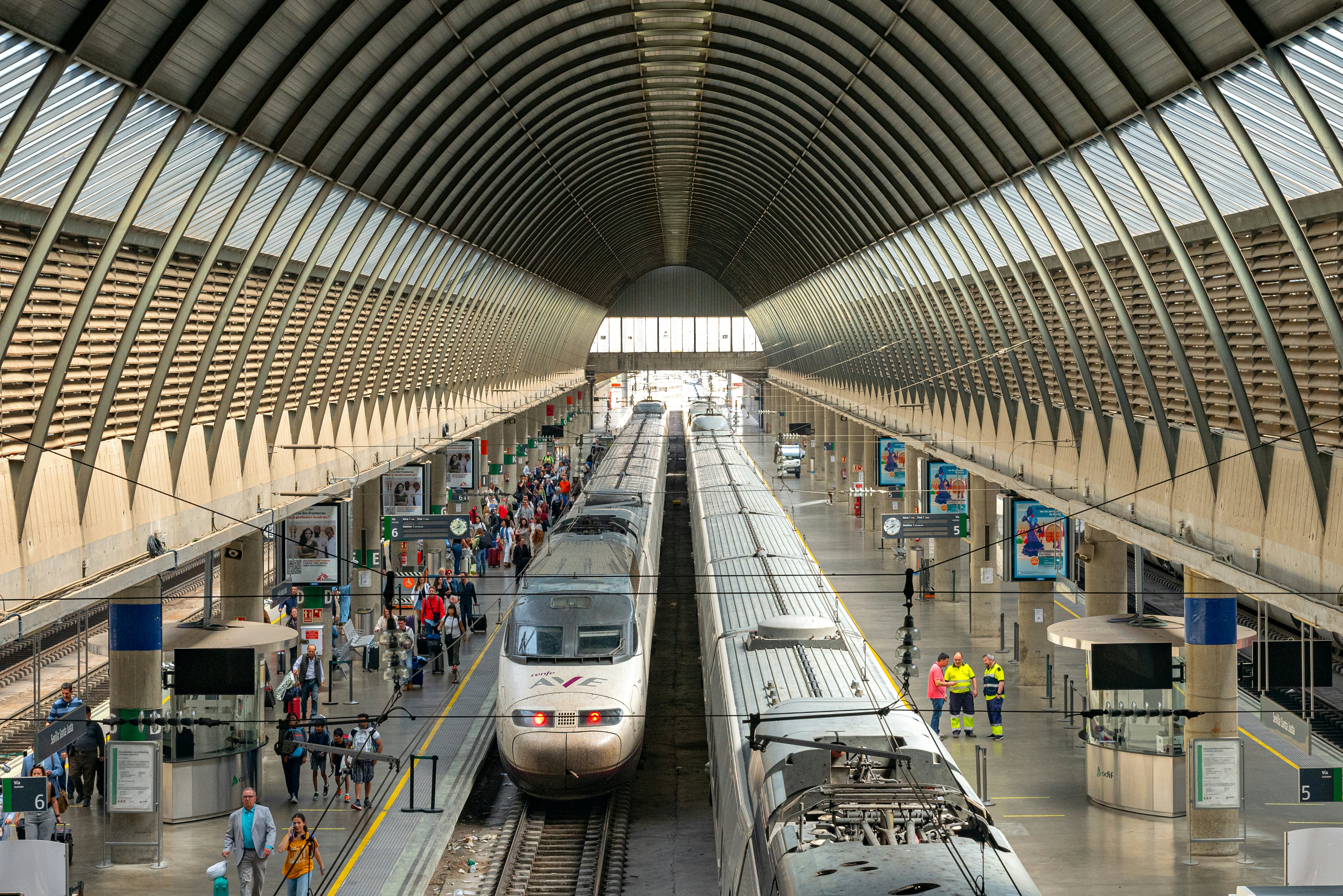 Two trains with AVE branding at a platform in a covered city station.